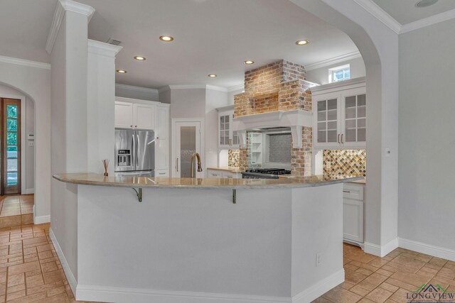 1719 Hg Mosley Pkwy, Longview, TX 75604 - kitchen featuring stainless steel refrigerator with ice dispenser, stone tile flooring, arched walkways, decorative backsplash, and crown molding