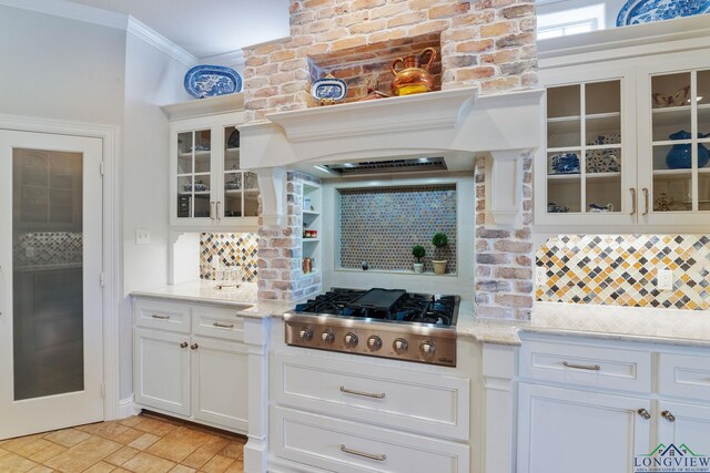 1719 Hg Mosley Pkwy, Longview, TX 75604 - kitchen with stainless steel gas stovetop, decorative backsplash, white cabinetry, glass insert cabinets, and ornamental molding