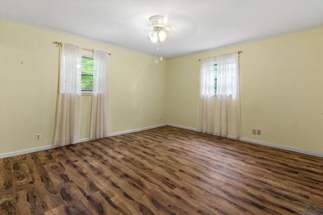 spare room featuring ceiling fan, a healthy amount of sunlight, ornamental molding, and dark wood-type flooring