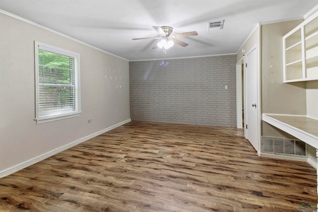 spare room featuring brick wall, ceiling fan, ornamental molding, and wood-type flooring