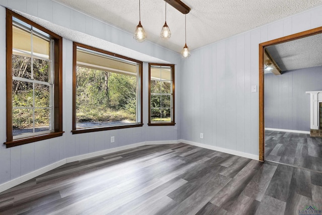 spare room with plenty of natural light, a textured ceiling, and dark wood-type flooring