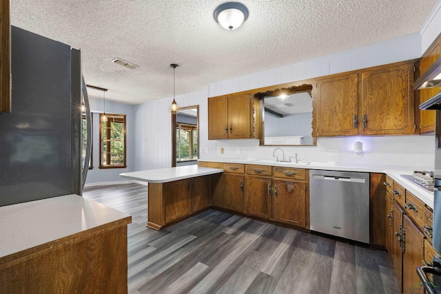 kitchen featuring sink, a textured ceiling, appliances with stainless steel finishes, decorative light fixtures, and kitchen peninsula