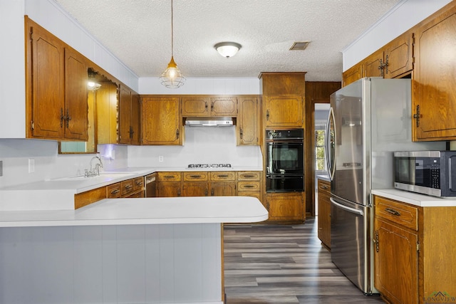 kitchen with sink, stainless steel appliances, kitchen peninsula, pendant lighting, and a textured ceiling