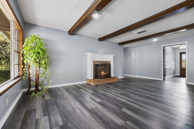 unfurnished living room with beamed ceiling, dark hardwood / wood-style floors, a fireplace, and a textured ceiling