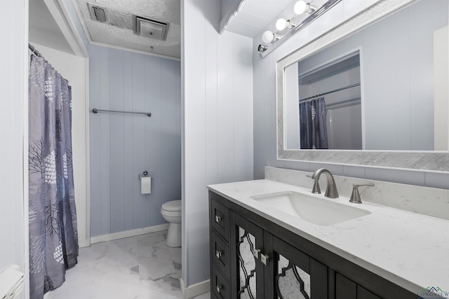 bathroom with vanity, toilet, a textured ceiling, and wooden walls