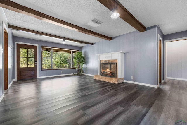 unfurnished living room with dark hardwood / wood-style floors, beam ceiling, a textured ceiling, and a brick fireplace