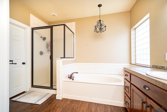 bathroom with wood-type flooring, vanity, shower with separate bathtub, and an inviting chandelier