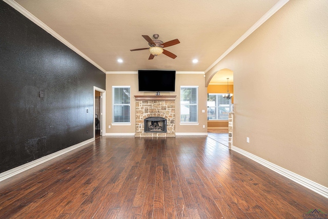 unfurnished living room with a stone fireplace, ceiling fan, dark hardwood / wood-style flooring, and crown molding