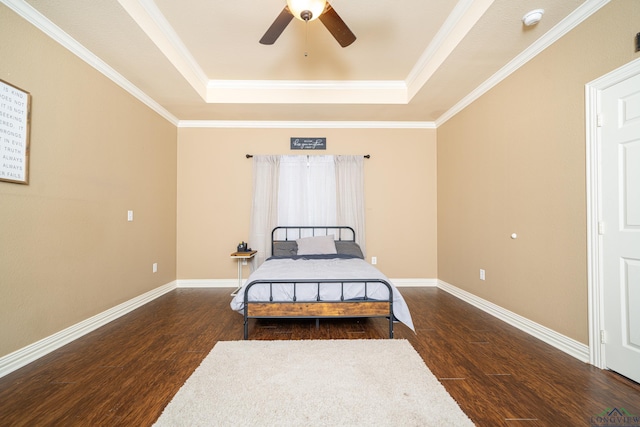 bedroom featuring dark hardwood / wood-style flooring, a tray ceiling, ceiling fan, and ornamental molding