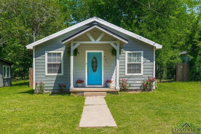 bungalow-style home with a front lawn and fence
