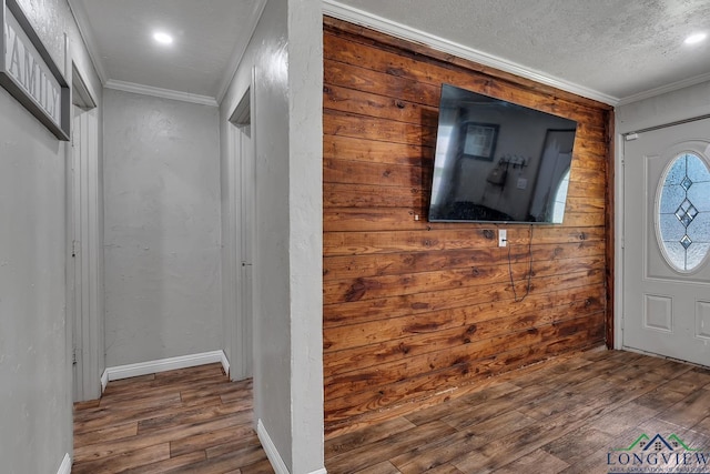 entrance foyer featuring a textured ceiling, recessed lighting, wood finished floors, crown molding, and wooden walls
