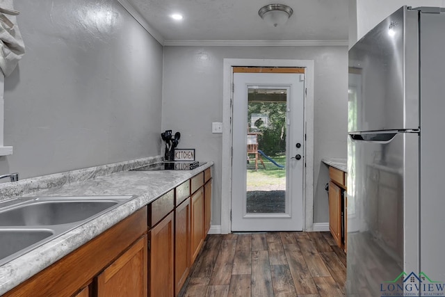 kitchen with freestanding refrigerator, brown cabinets, ornamental molding, and dark wood finished floors
