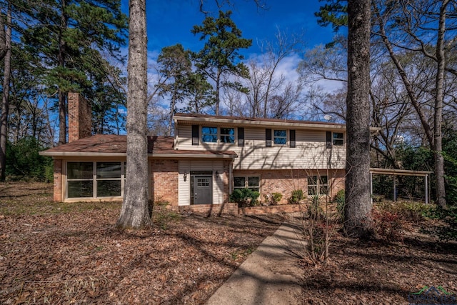 view of front of property with a sunroom, a chimney, and brick siding