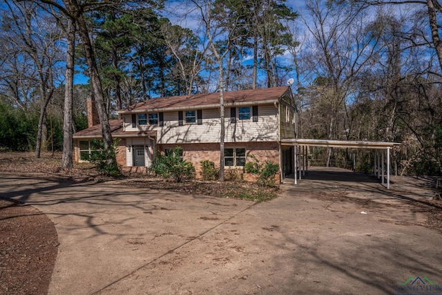 view of front of house with an attached carport, brick siding, and driveway