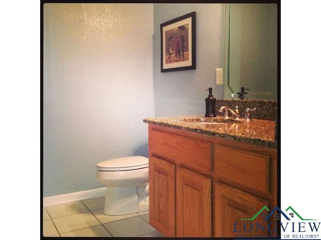 bathroom with toilet, vanity, and tile patterned flooring