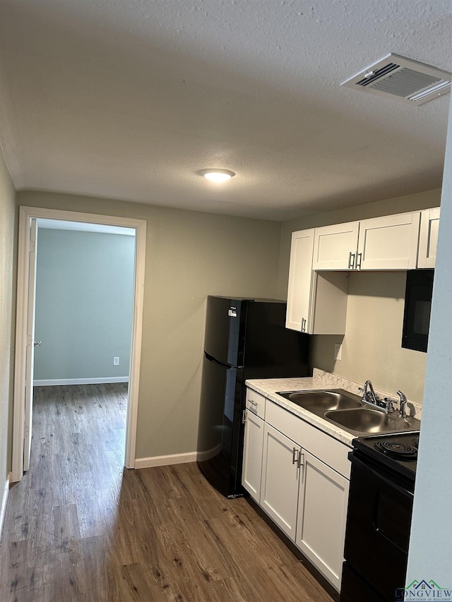 2001 E 20th, Hooks, TX 75561 - kitchen with black appliances, a sink, dark wood-style flooring, white cabinets, and a textured ceiling