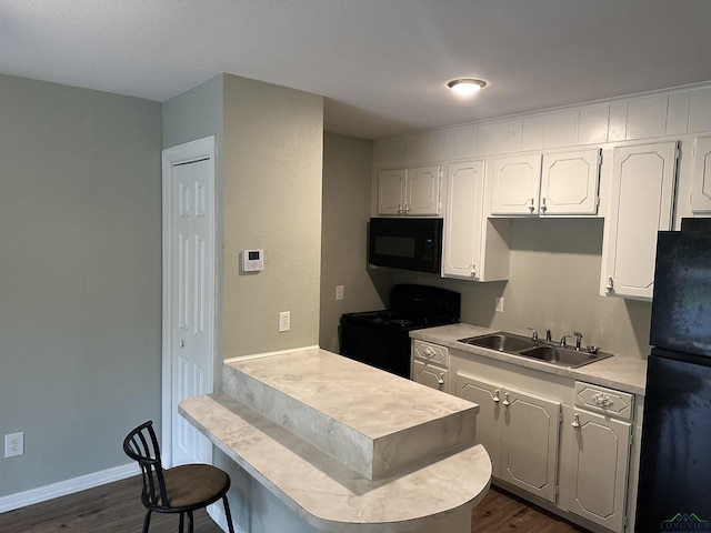 2001 E 20th, Hooks, TX 75561 - kitchen featuring black appliances, a sink, dark wood finished floors, a breakfast bar, and a peninsula
