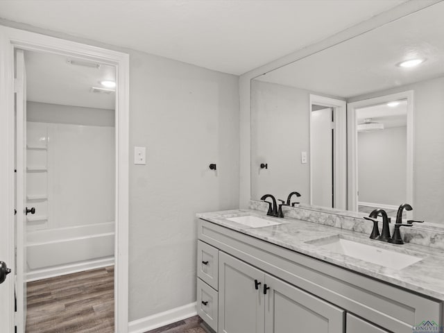 bathroom with double vanity, baseboards, a sink, and wood finished floors