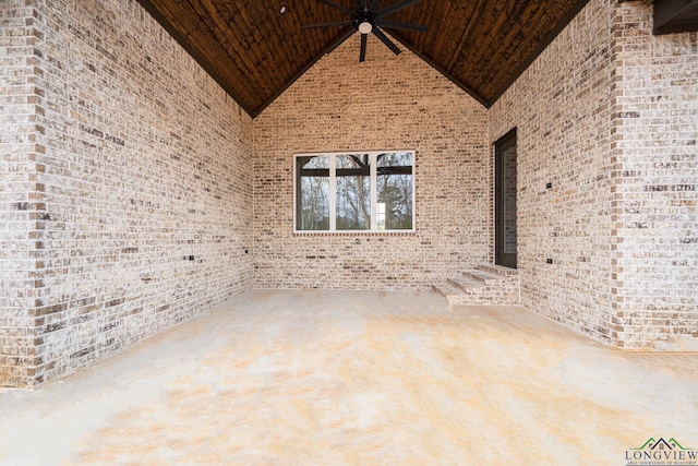 empty room featuring high vaulted ceiling, wooden ceiling, brick wall, and ceiling fan