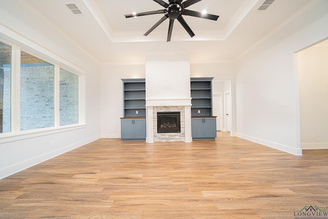 unfurnished living room with a raised ceiling, ceiling fan, a fireplace, and ornamental molding