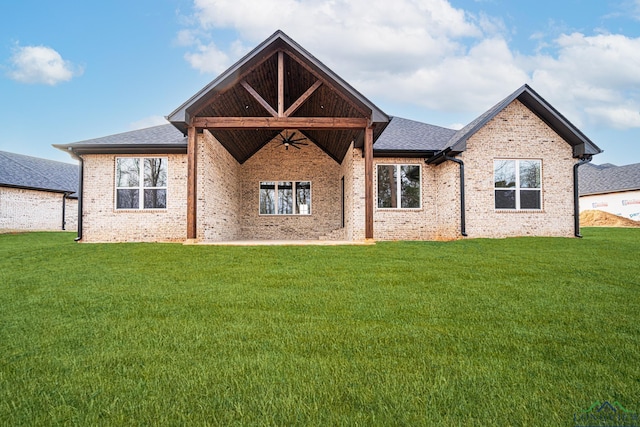 rear view of property featuring ceiling fan and a yard