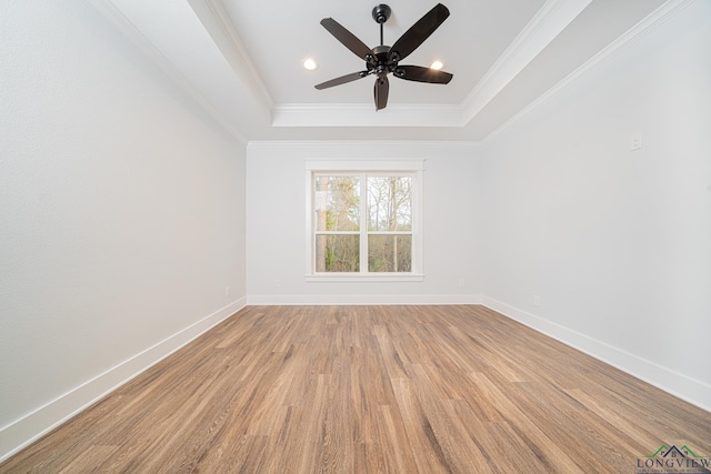 empty room with light wood-type flooring, ceiling fan, crown molding, and a tray ceiling