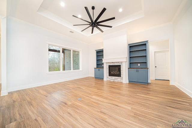 unfurnished living room featuring a fireplace, built in features, a raised ceiling, and ceiling fan