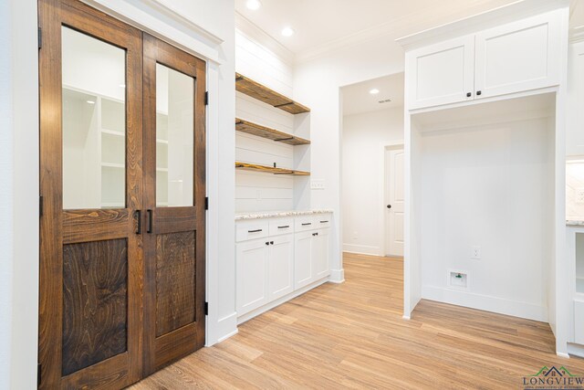 corridor with crown molding, french doors, and light wood-type flooring