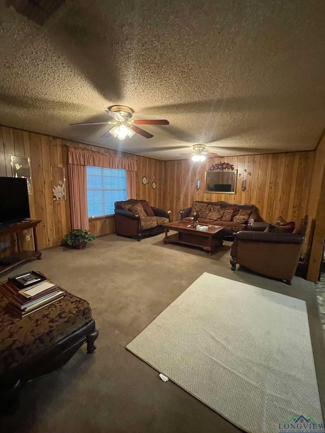 carpeted living area with ceiling fan, wood walls, and a textured ceiling