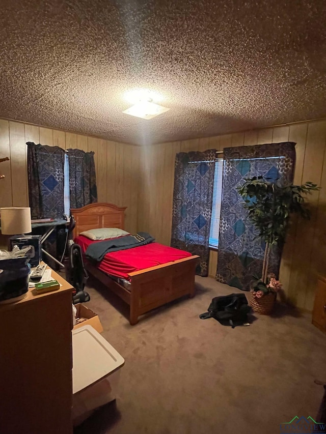 bedroom with a textured ceiling, wood walls, and carpet flooring