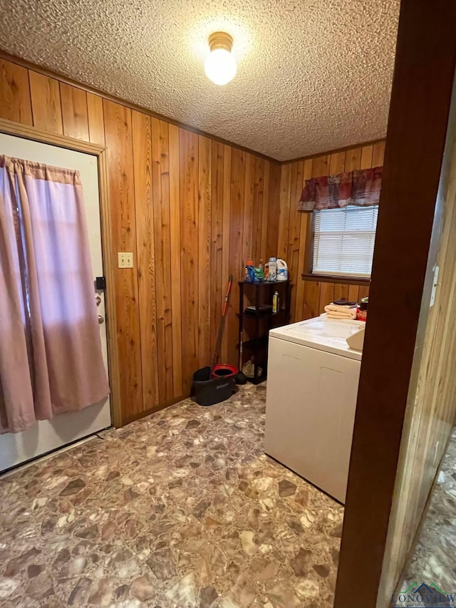 clothes washing area with laundry area, washer / clothes dryer, a textured ceiling, and wood walls