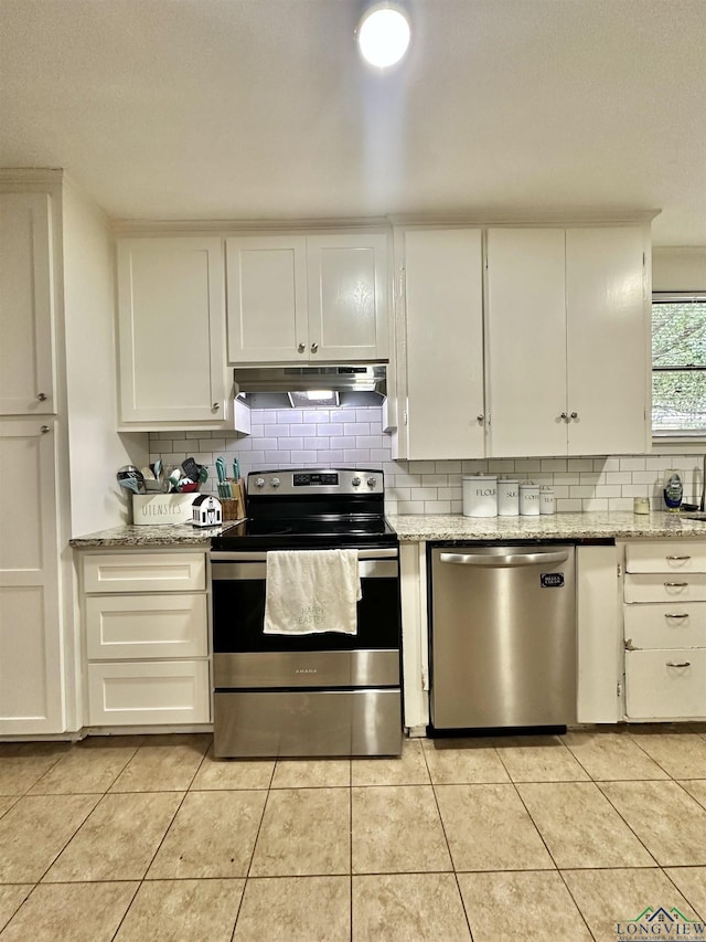 kitchen featuring light stone counters, white cabinets, stainless steel appliances, and light tile patterned floors