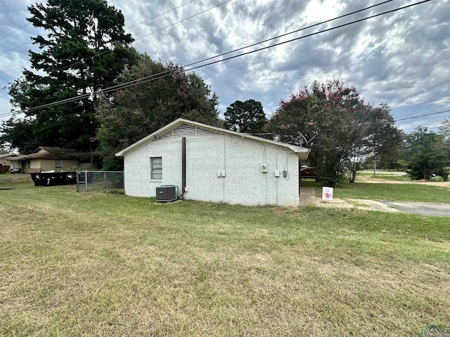 view of side of home featuring a yard and central AC