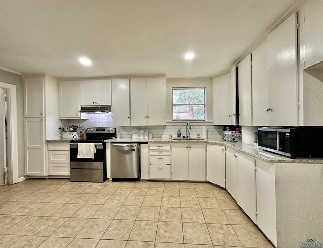 kitchen featuring backsplash, stainless steel appliances, sink, light tile patterned floors, and white cabinets