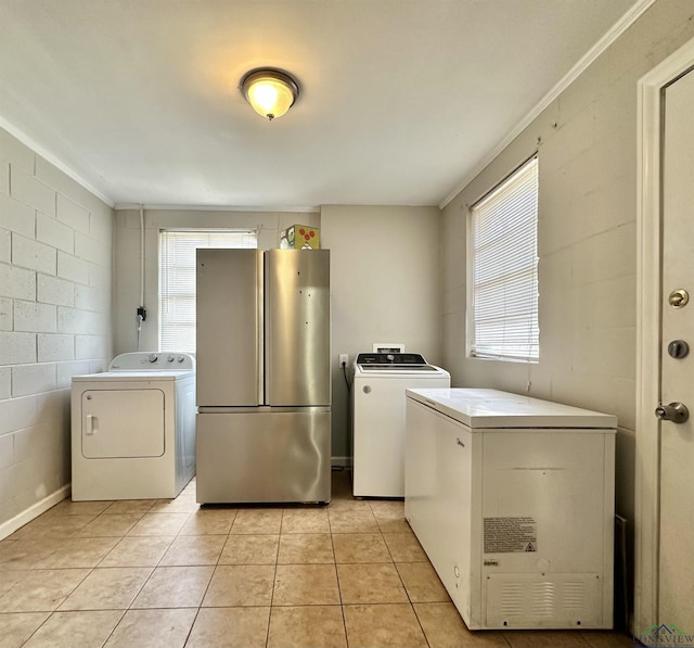 laundry area featuring light tile patterned floors, crown molding, and washing machine and clothes dryer