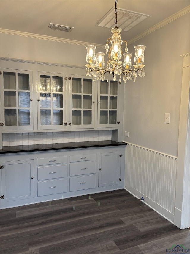 unfurnished dining area featuring a chandelier, dark hardwood / wood-style floors, and ornamental molding