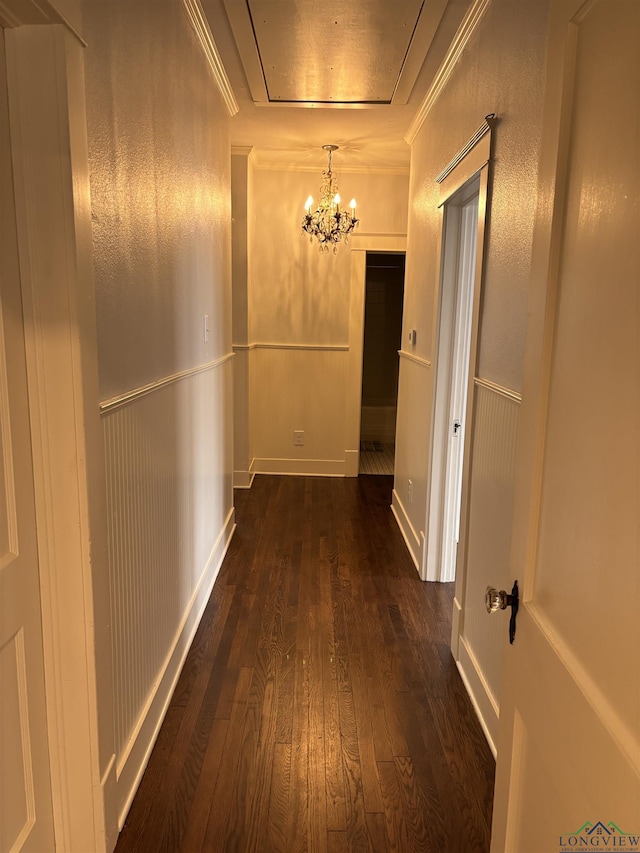 hall featuring a notable chandelier, dark hardwood / wood-style floors, and ornamental molding