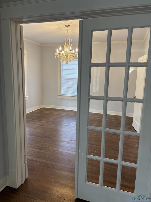 empty room featuring a notable chandelier, dark hardwood / wood-style floors, and ornamental molding