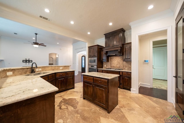 kitchen with dark brown cabinetry, stainless steel appliances, ceiling fan, sink, and a center island