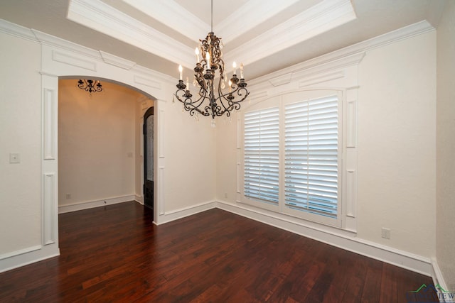 spare room featuring a tray ceiling, crown molding, dark hardwood / wood-style floors, and an inviting chandelier