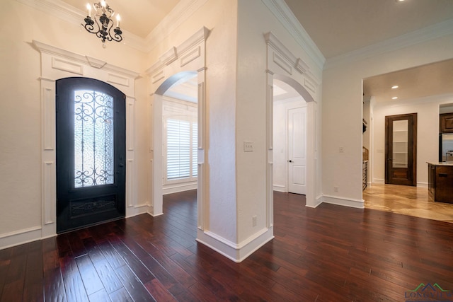 foyer with a notable chandelier, dark hardwood / wood-style floors, and crown molding