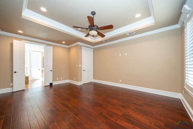 spare room featuring dark wood-type flooring, a raised ceiling, ceiling fan, and crown molding