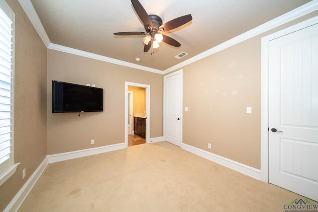 unfurnished bedroom with light colored carpet, ensuite bath, ceiling fan, and ornamental molding