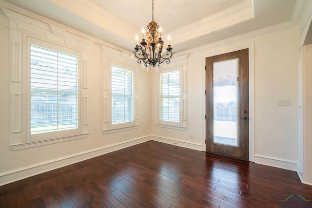 unfurnished dining area featuring a raised ceiling, dark hardwood / wood-style flooring, ornamental molding, and a notable chandelier