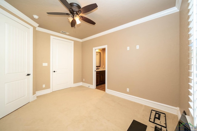 unfurnished bedroom featuring ceiling fan, crown molding, carpet floors, and ensuite bathroom