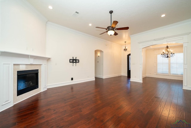 unfurnished living room featuring crown molding, a high end fireplace, dark wood-type flooring, and ceiling fan with notable chandelier