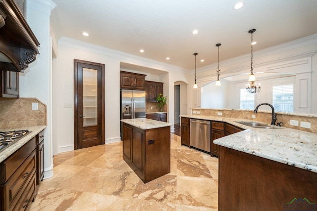 kitchen featuring a center island, backsplash, sink, appliances with stainless steel finishes, and decorative light fixtures