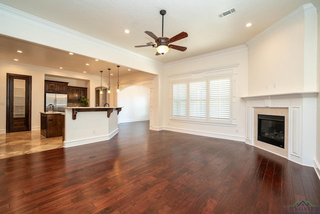 unfurnished living room featuring dark wood-type flooring, ceiling fan, crown molding, and a premium fireplace