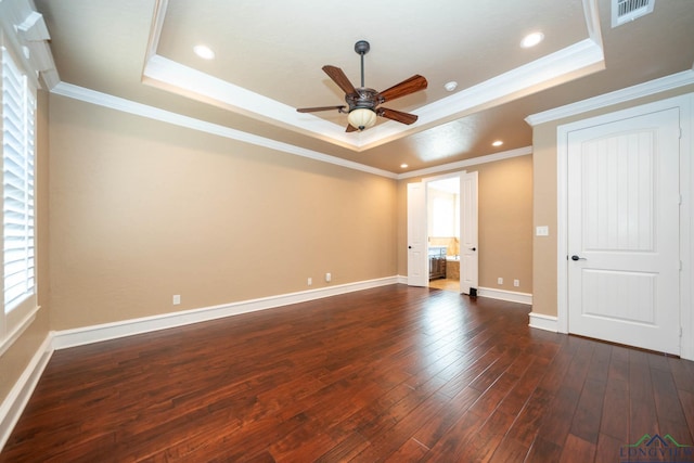 interior space with dark wood-type flooring, a raised ceiling, ceiling fan, and crown molding