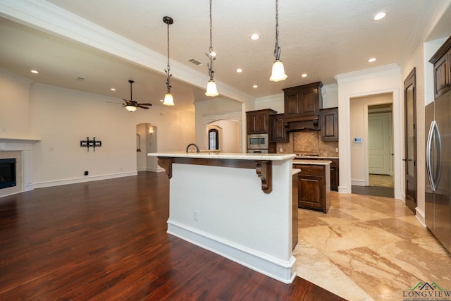 kitchen with a breakfast bar, pendant lighting, dark brown cabinets, and a large island